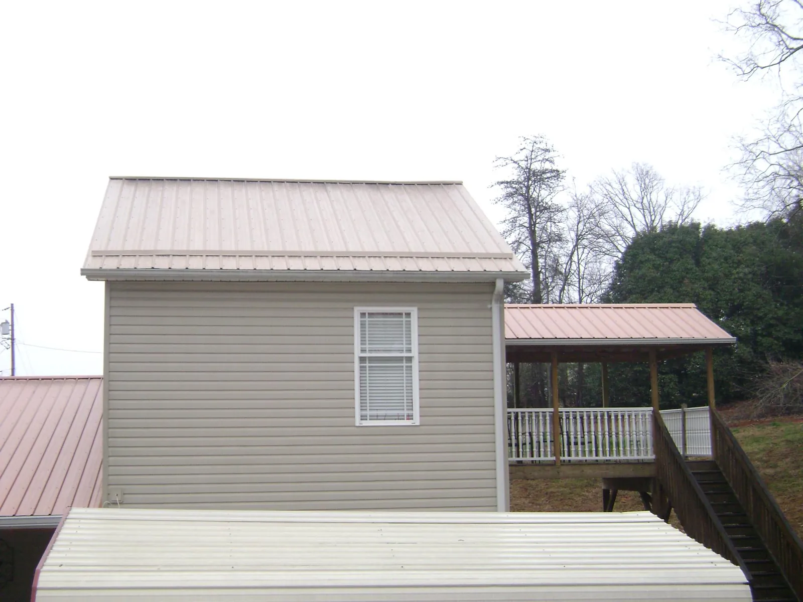 Tan metal roofs on a two story addition and attached porch, from a Roof Replacement job in Anna